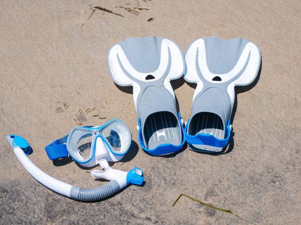 masque, tuba et palmes posés sur le sable, le matériel de snorkeling à emporter